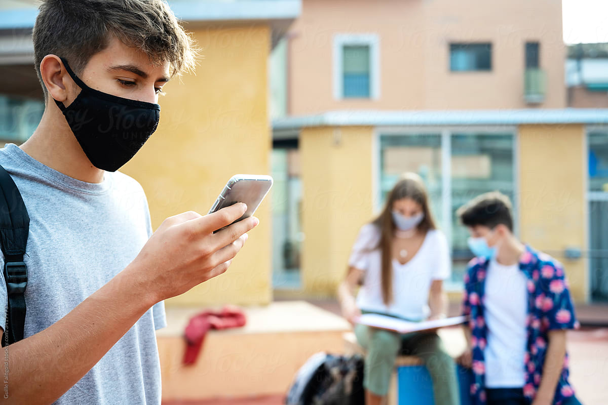 Student wearing mask using phone