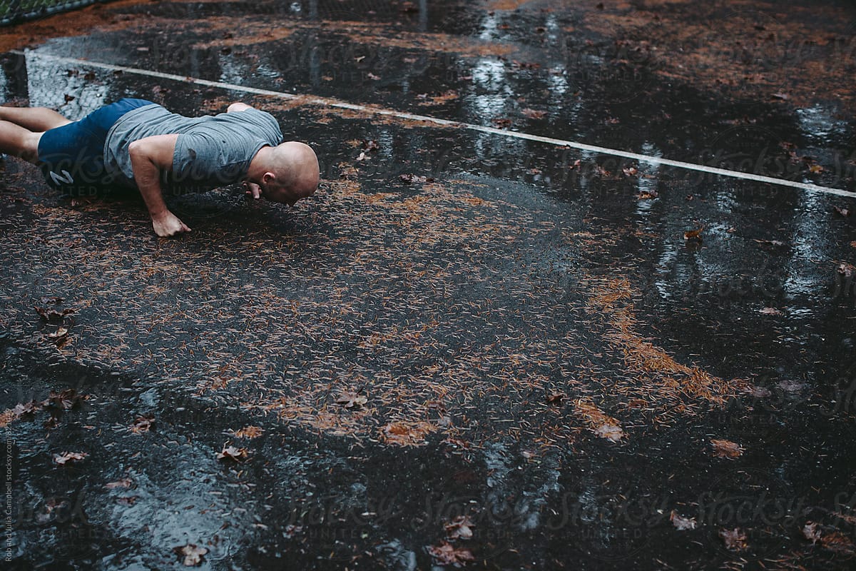 Man doing push-ups on fists on wet ground outside