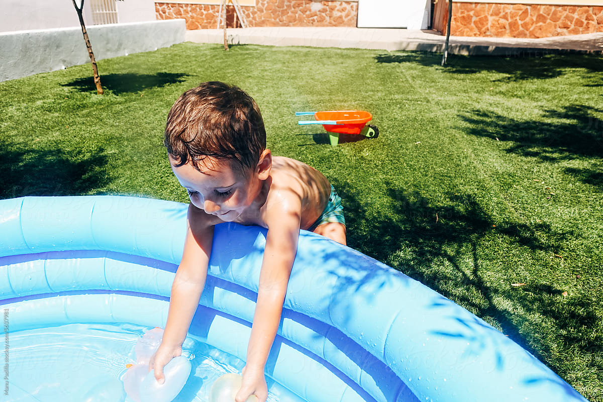 Boy playing with balloons in inflatable pool