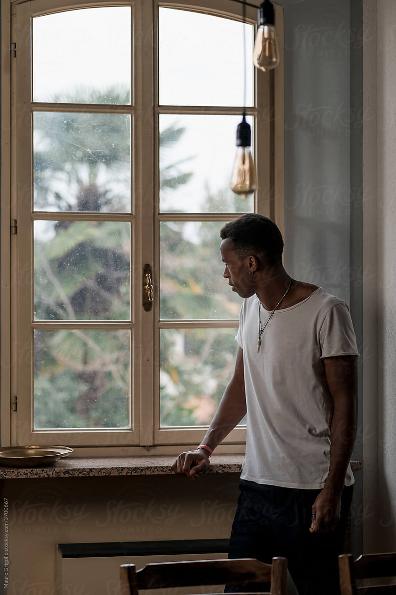 Pensive Black man At Home looking out of the window.