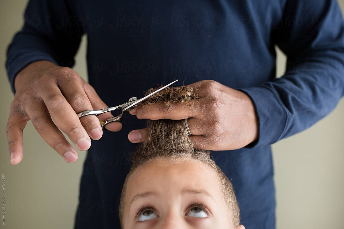 Closeup of man trimming child\'s curly hair