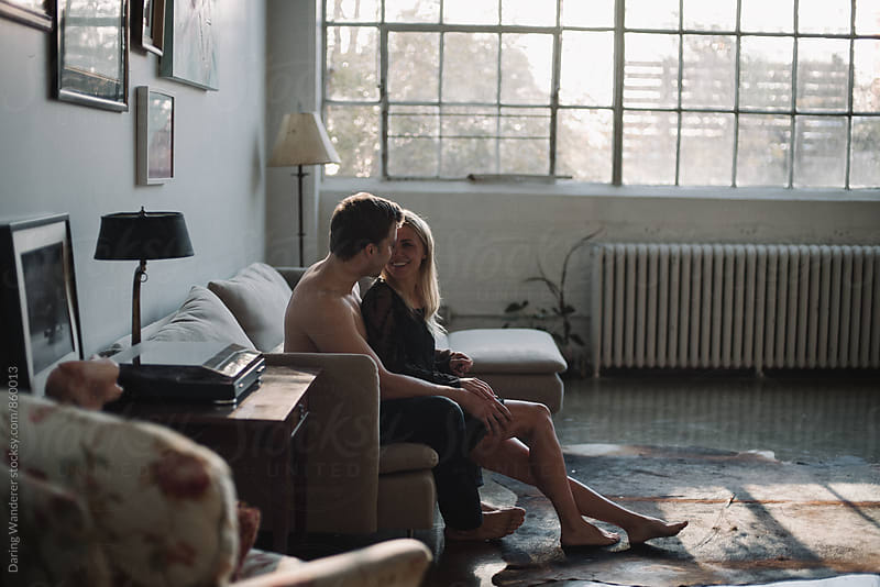 Young couple sitting together hugging on couch in industrial loft