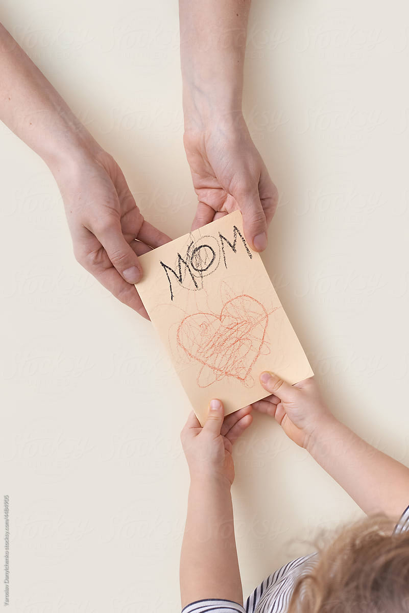 Close up of child and mother hands holding greeting card