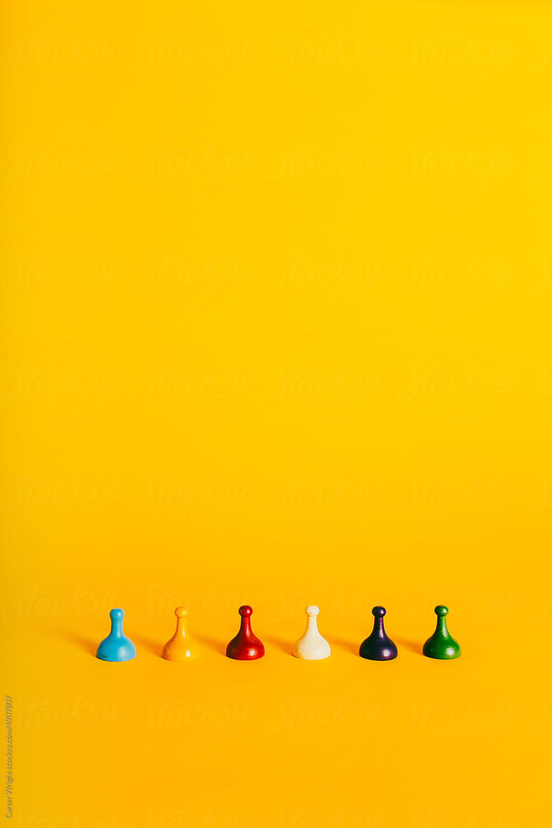 Colorful Board Game pieces horizontally on a vibrant yellow background