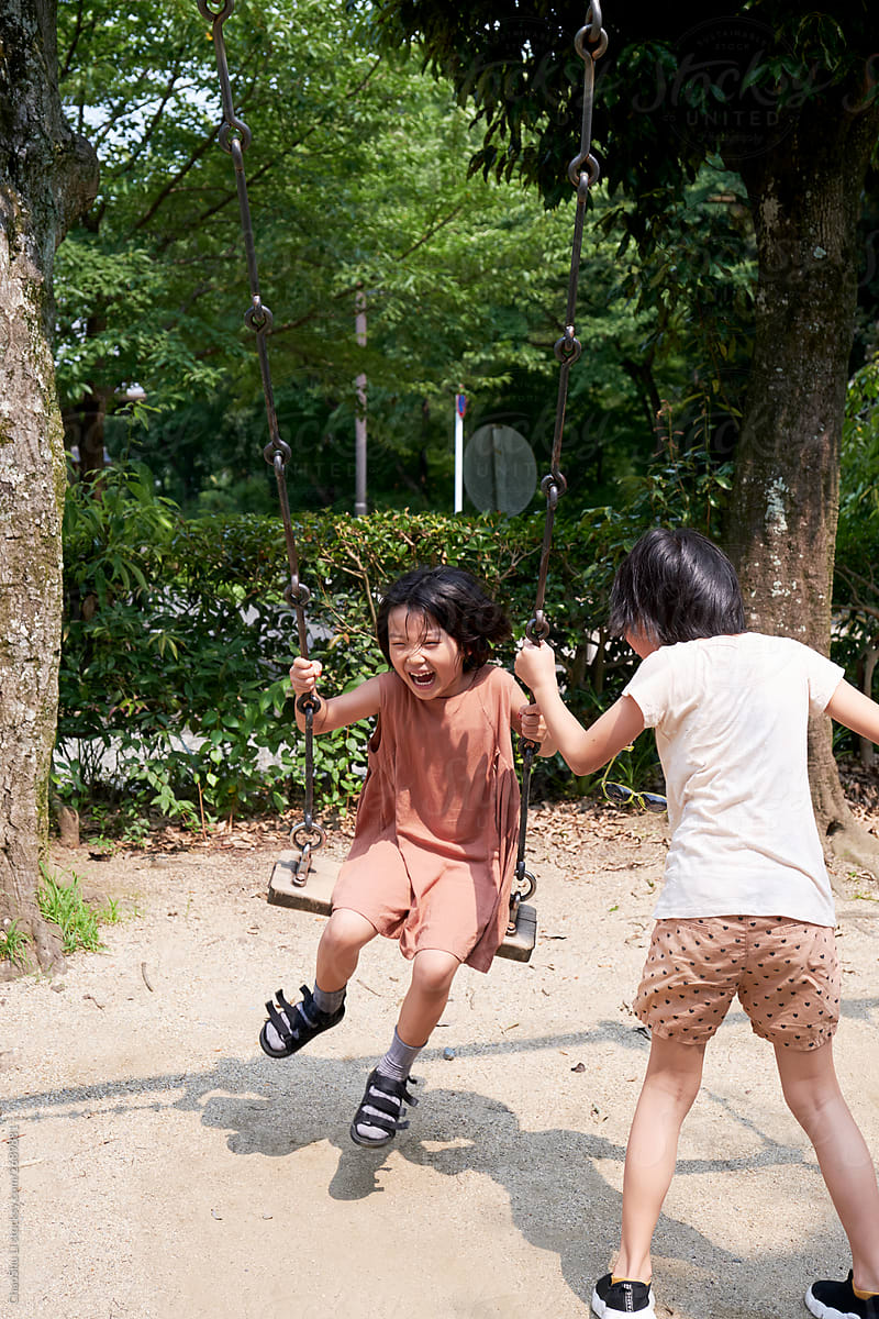 Asian little girls swinging in a lovely public small park in Japan