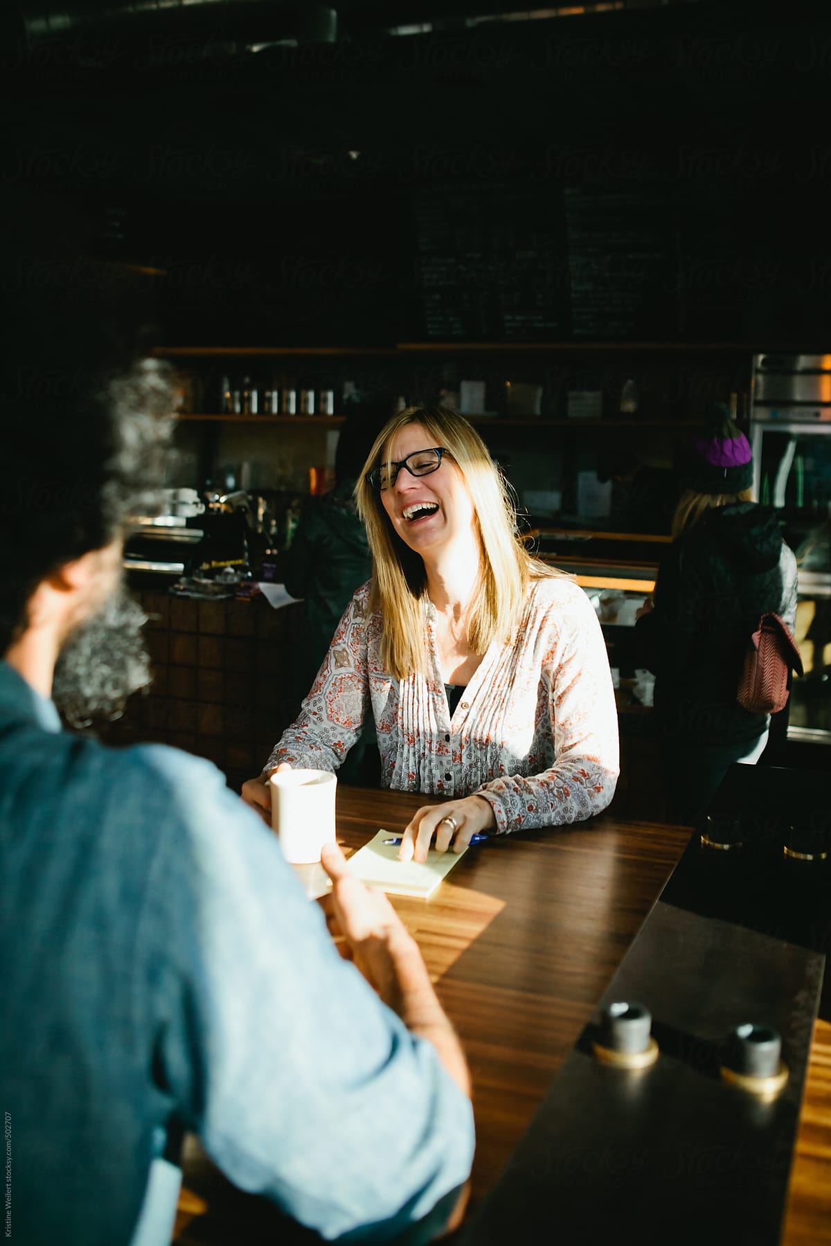 Woman laughing while meeting with a man over coffee