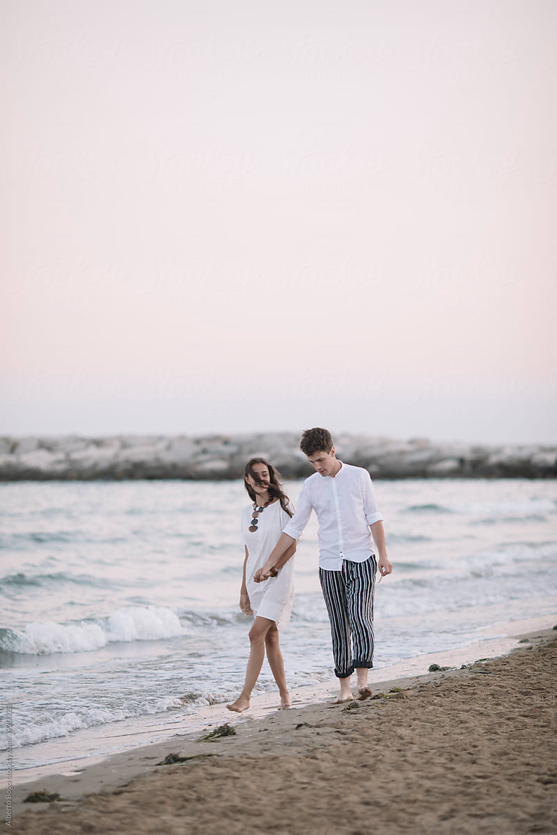 Young Couple In Love Walking On Te Shoreline During Sunset
