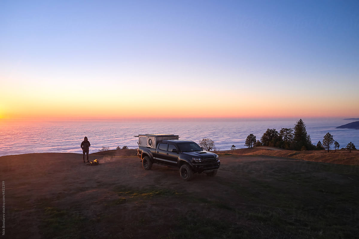 Vehicle and traveler on seashore at sunset