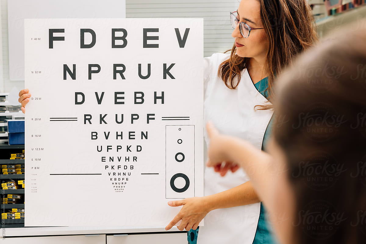 Crop woman oculist near vision test chart with patient