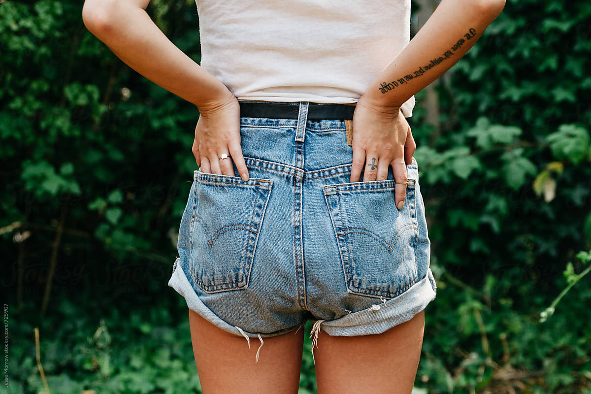 young woman with hands in back pockets of cut off blue jeans