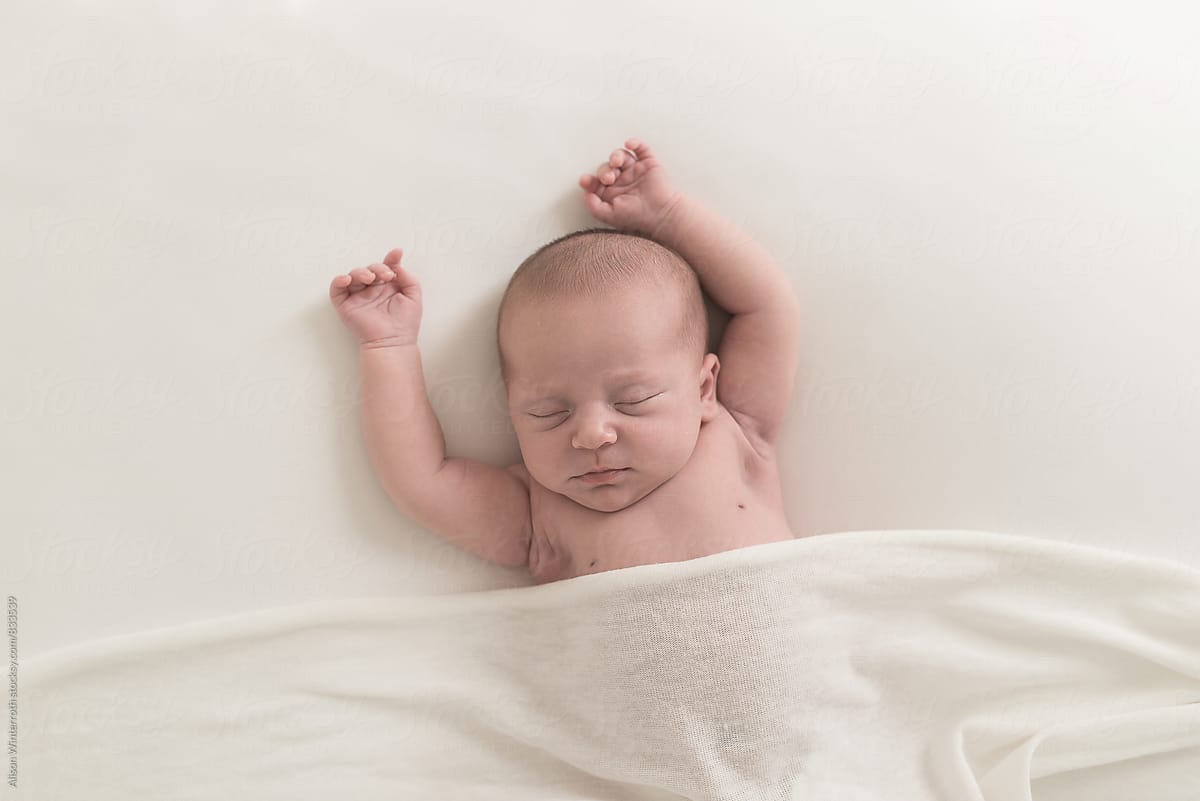 Newborn Sleeping Under A White Cover