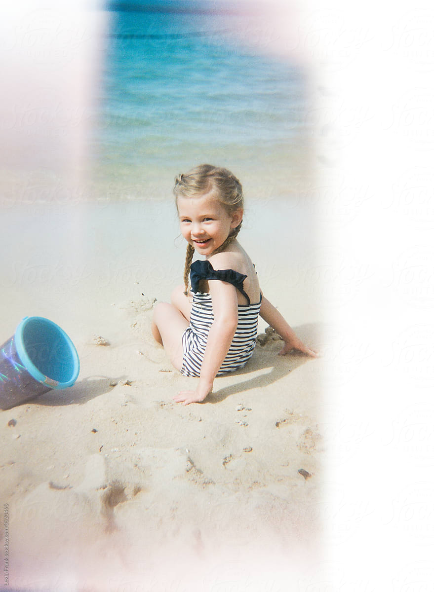 little girl digs in the sand on the beach on film