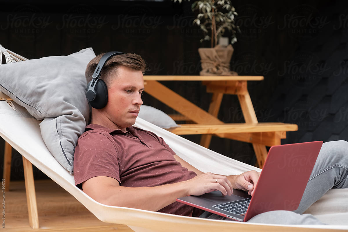 Male freelancer lying in hammock on terrace