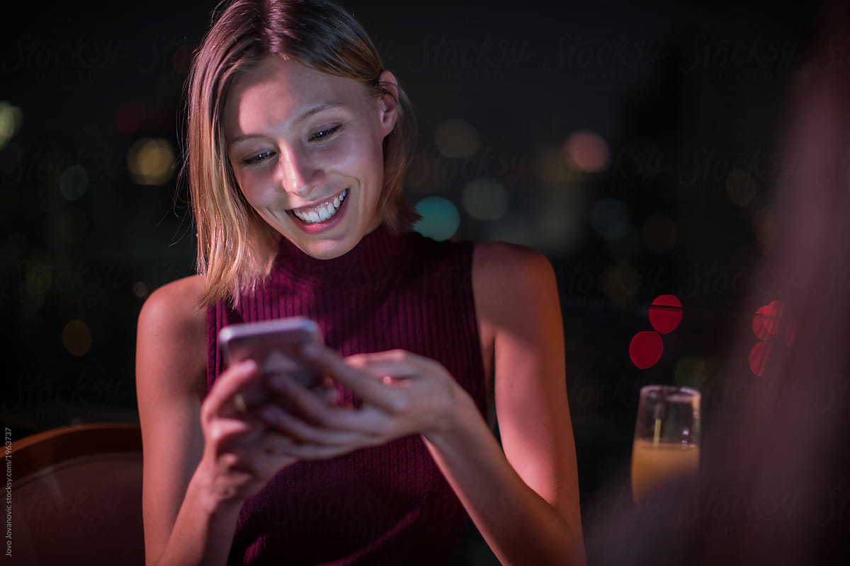 Woman Smiling While Using Her Phone By Stocksy Contributor Jovo Jovanovic Stocksy