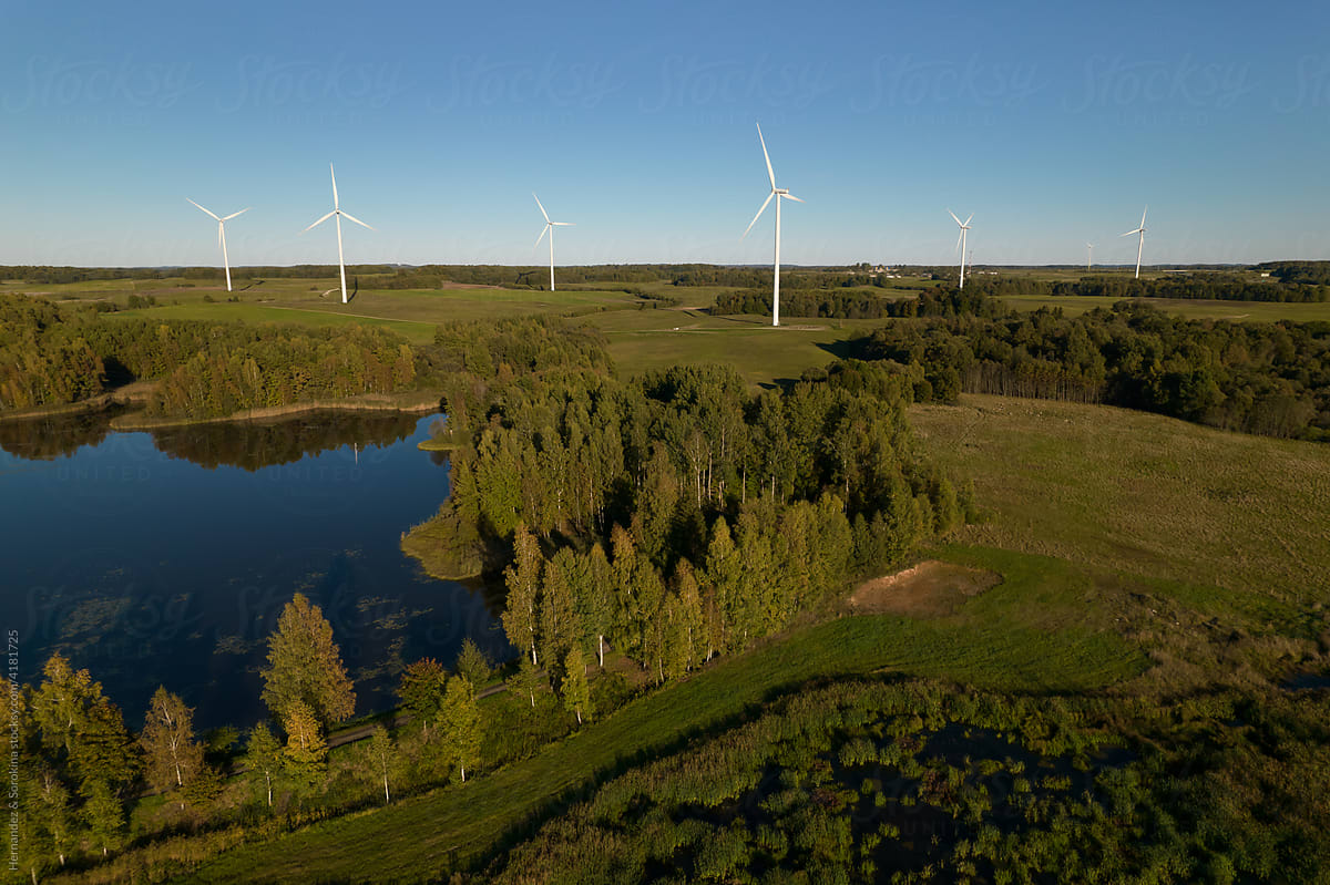 Windmill Plant Surrounded By Forest And Lake
