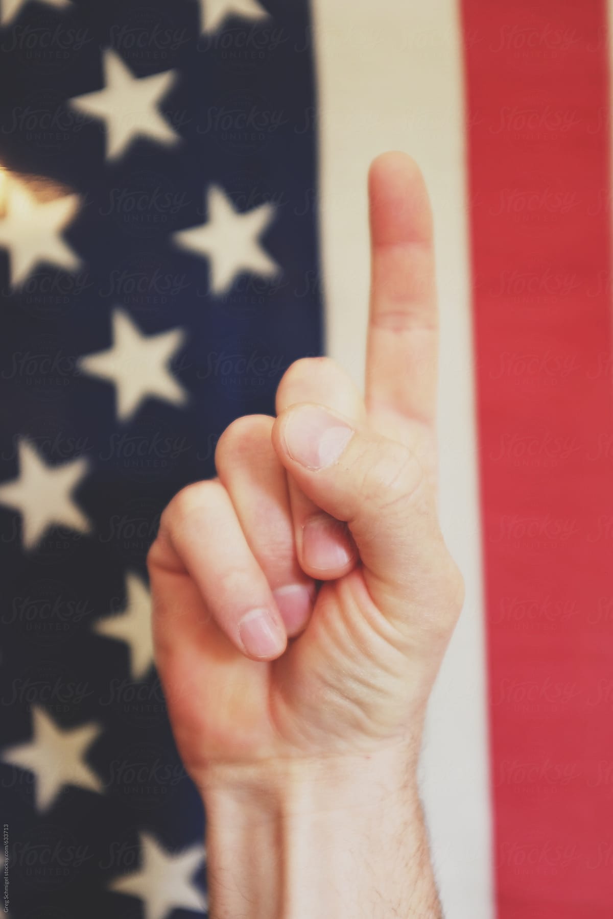 Hand and finger number one gesture in front of an old American Flag