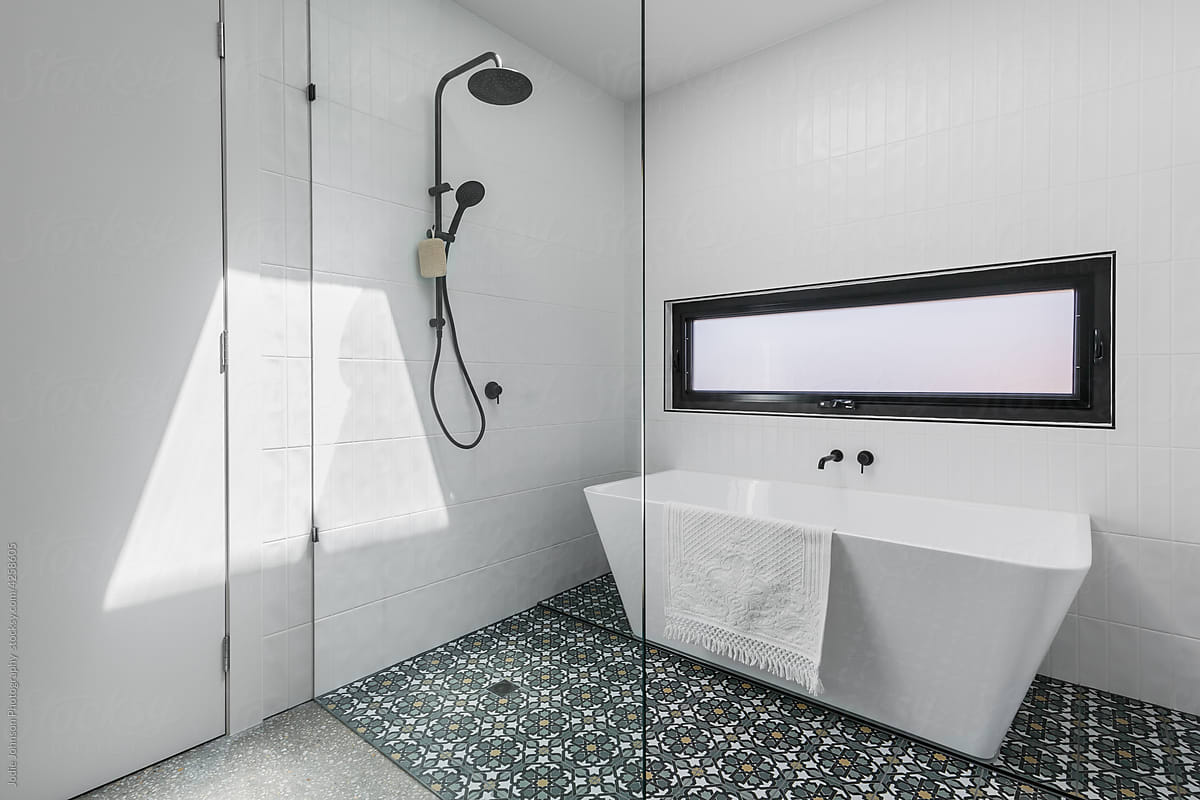 White bathroom shower and bath with decorative floor tile