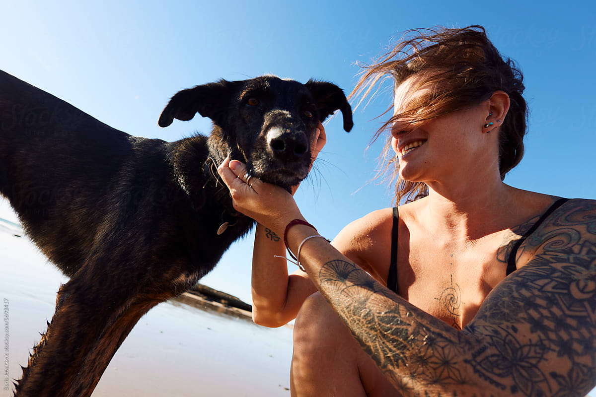 Tattooed woman cuddles her dog