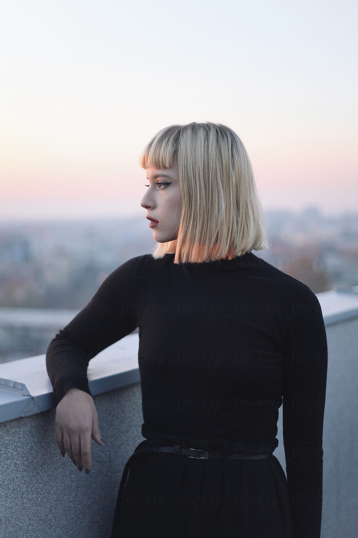 Young stylish woman on the roof of the building during sunset