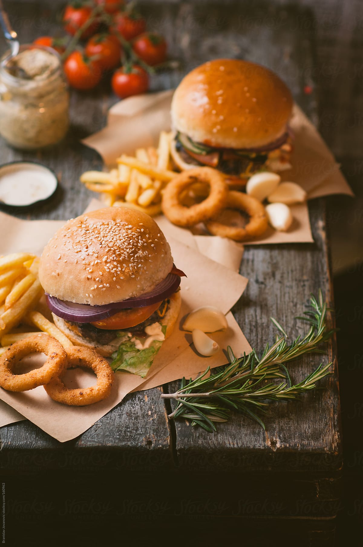 Hamburgers With Fries And Onion Rings On The Rustic Table