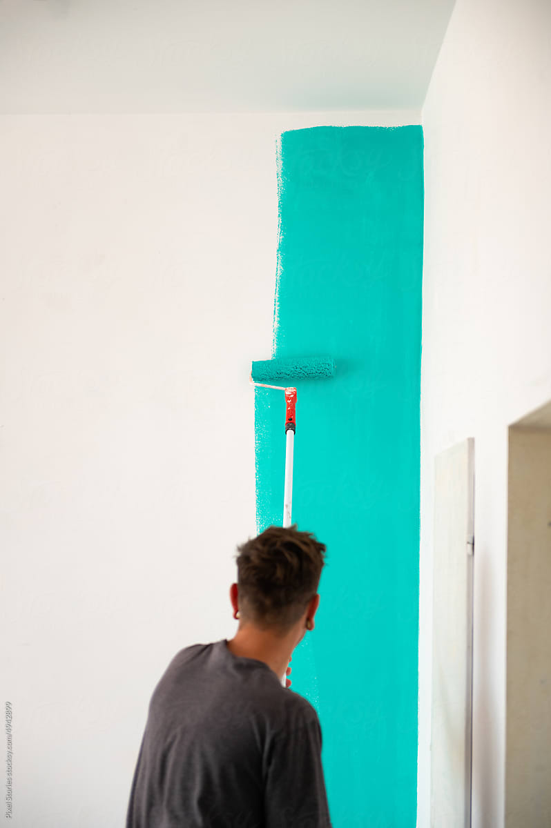 Graffiti artist preparing wall for mural with turquoise paint
