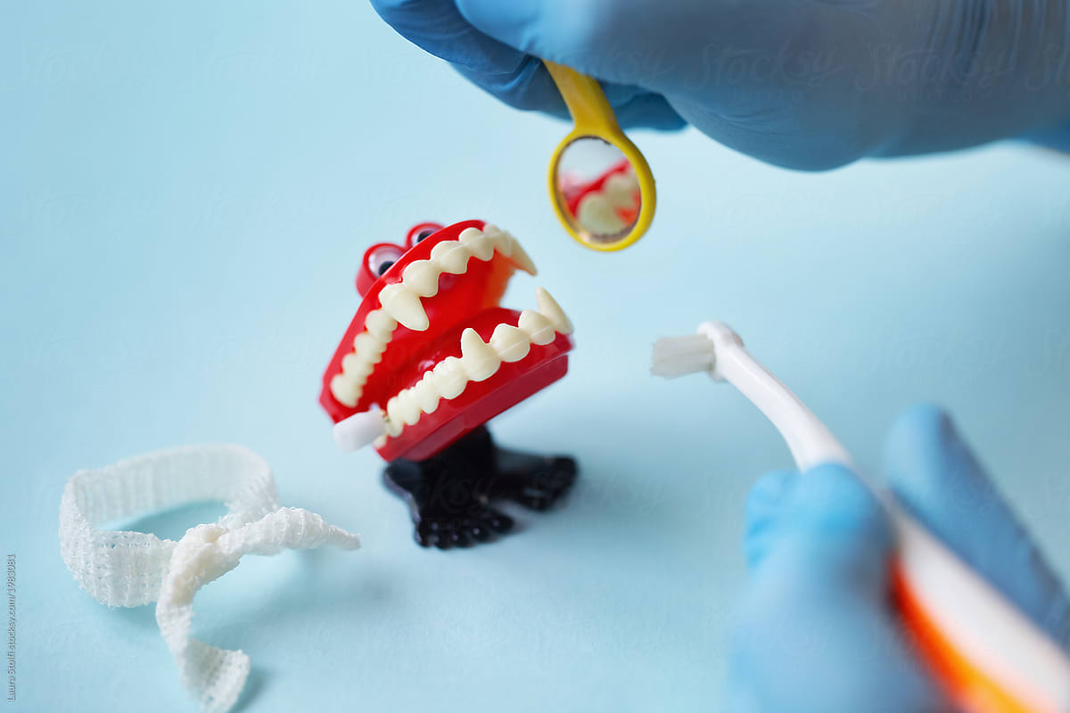 Closeup of gloved dentist\'s hands visiting vampire wind up teeth toy