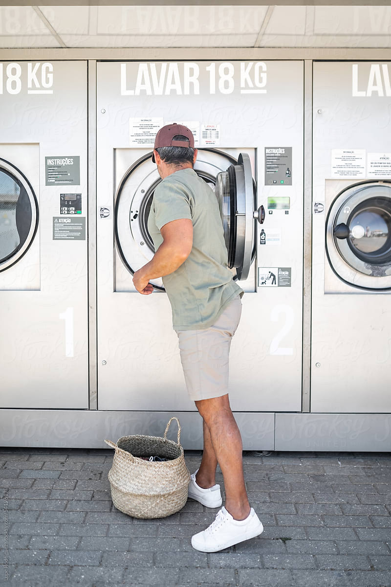 young man doing laundry in a city laundry