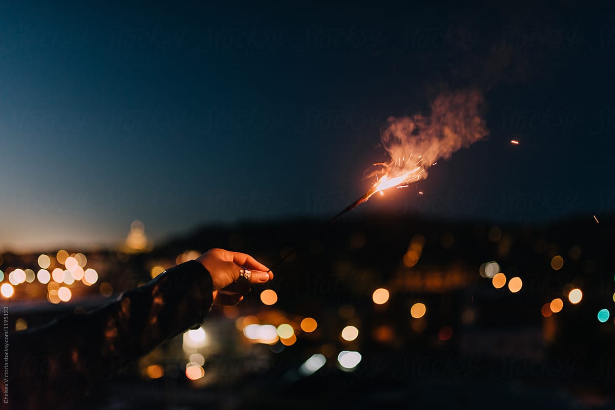 A woman holding a sparkler in the city