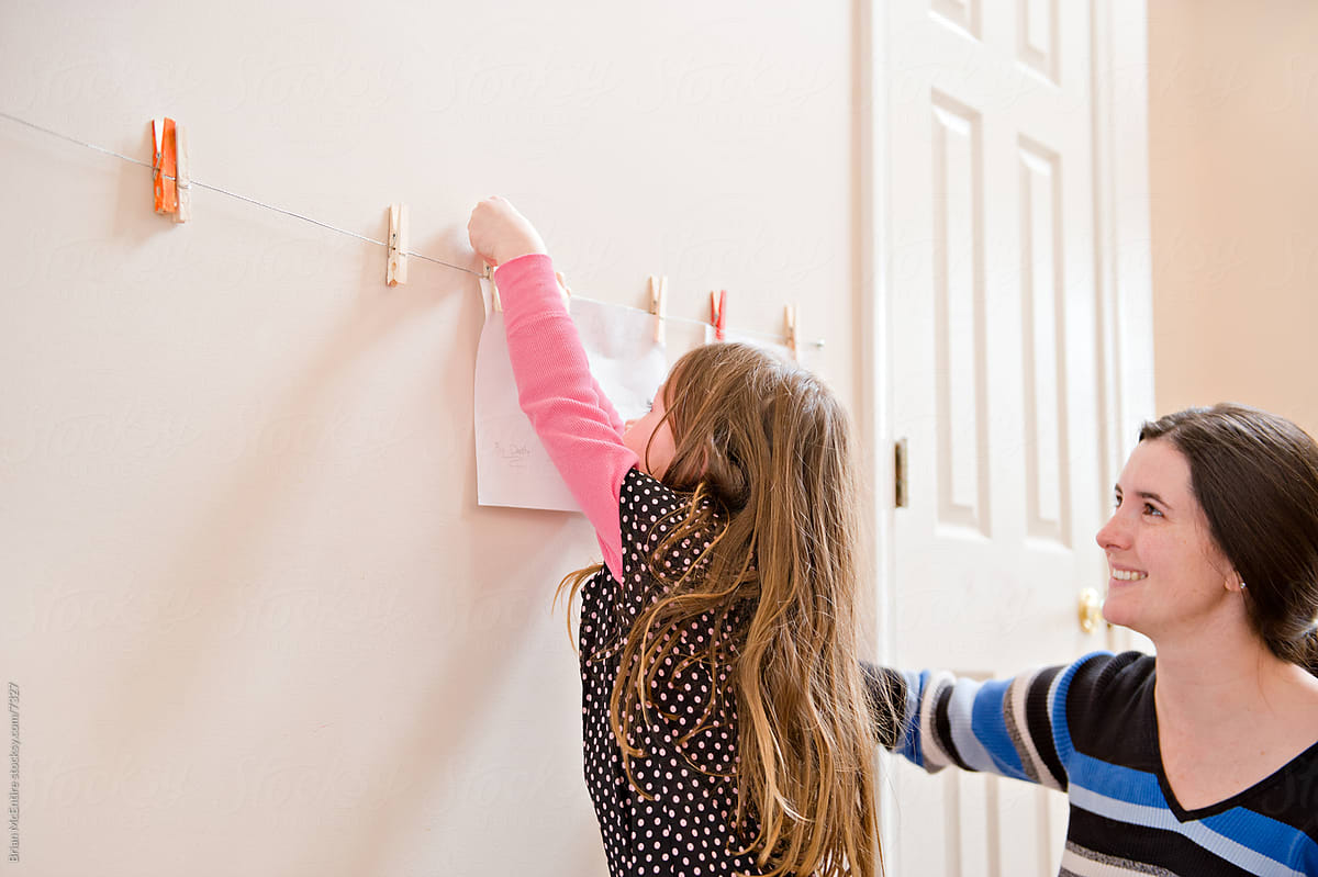 Young Girl Hanging Art with her Mom