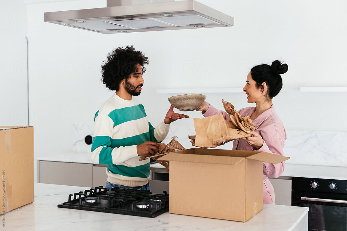 Multiracial couple unpacking dishware in kitchen