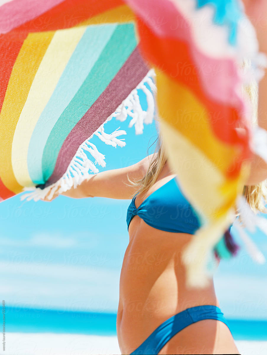 Girl In Bikini Taking Shirt Off At Beach With Ocean by Stocksy Contributor  Wendy Laurel - Stocksy