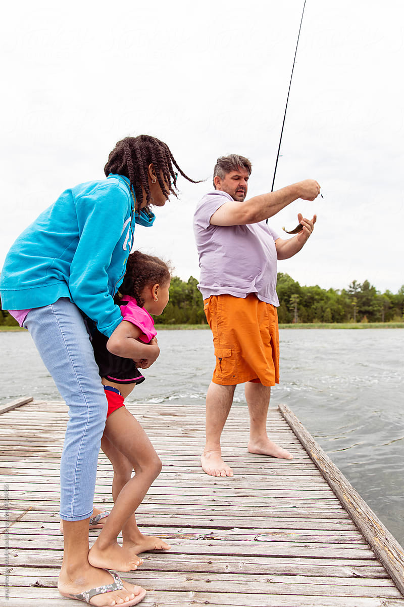 Kids watching their dad fish while at a lake