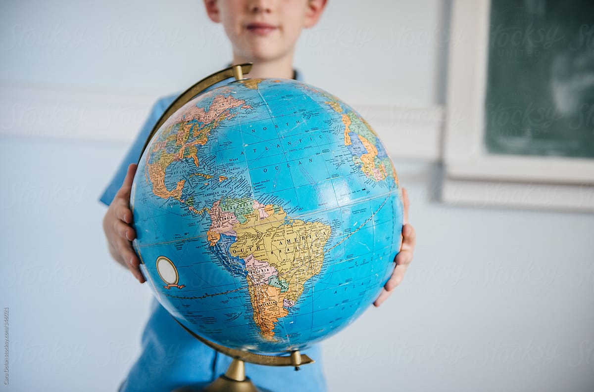 Student in classroom holds a globe
