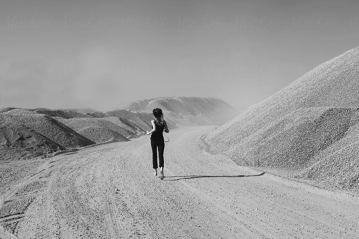 Black and white photo of a girl running in the desert