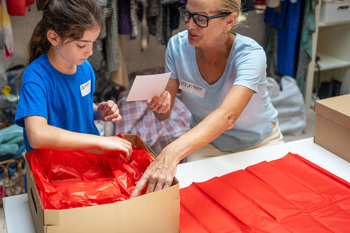 mature woman and her granddaughter packing gifts at a donation center