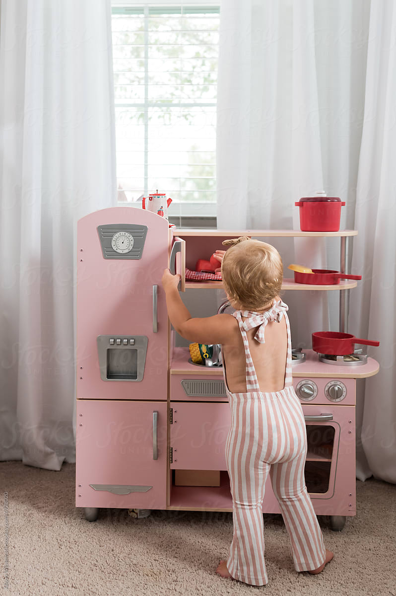 Girl plays with her toy kitchen