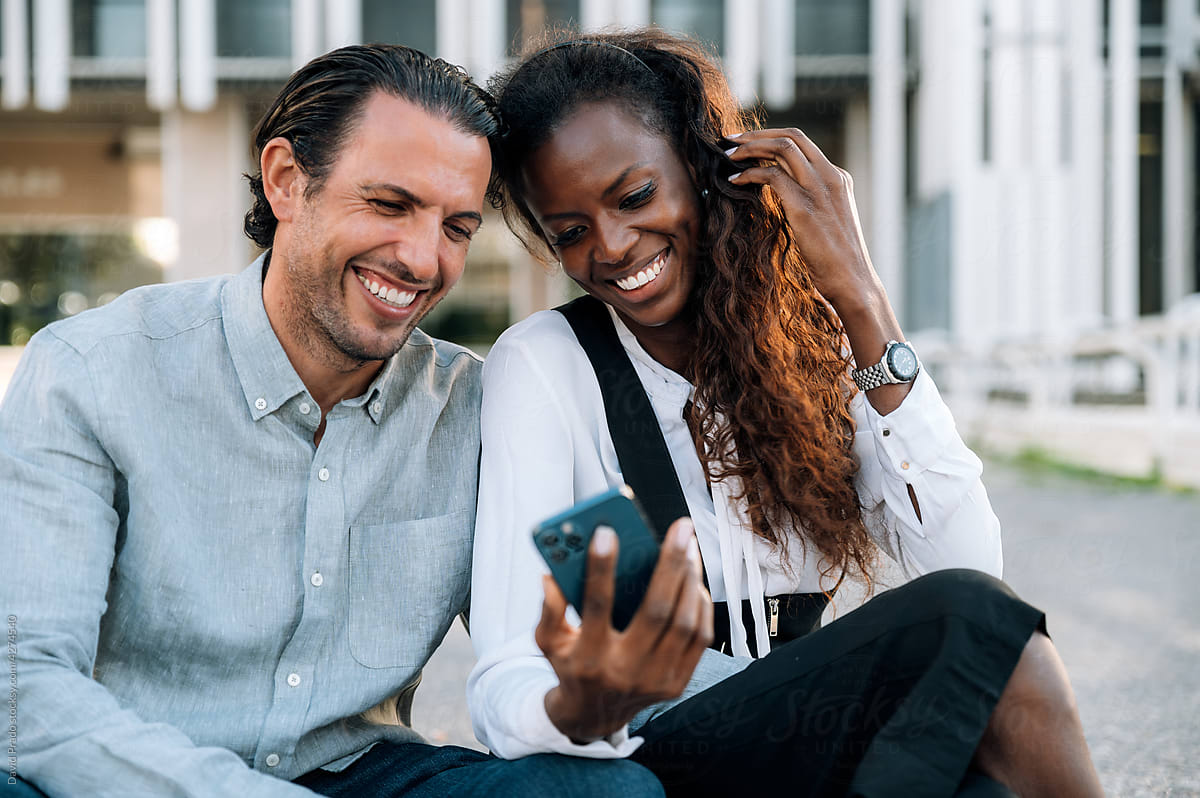 Cheerful multiethnic couple browsing smartphone