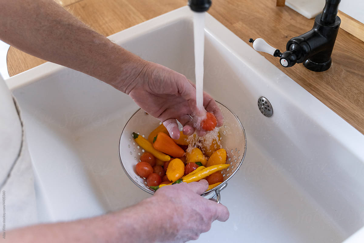 Senior man washing vegetables at kitchen sink