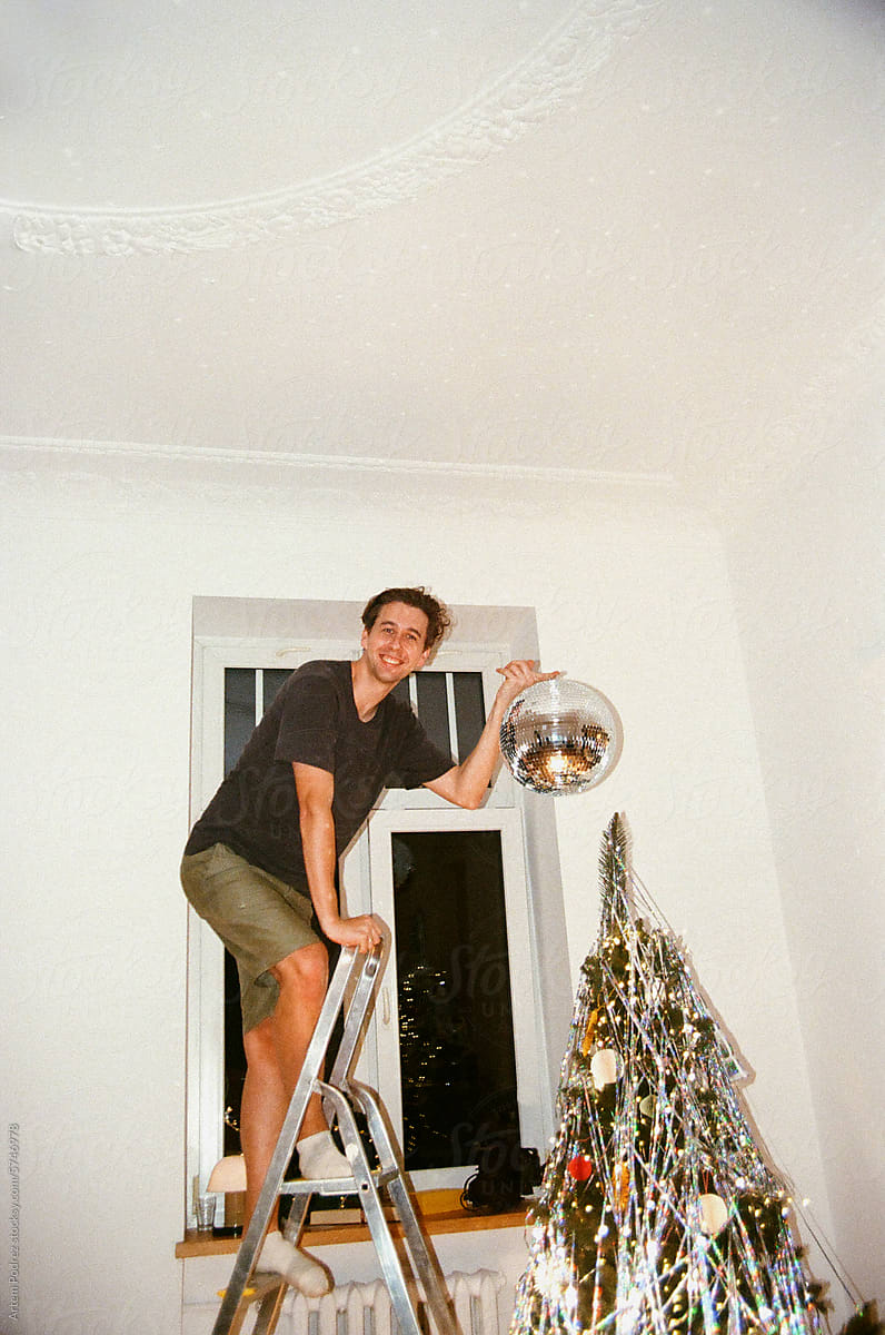 Man Decorating Tree with Disco Ball
