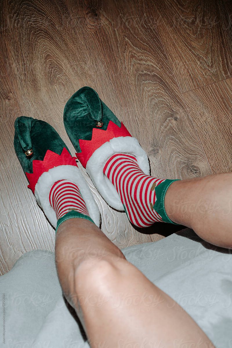man in the edge of the bed wearing elf shoes