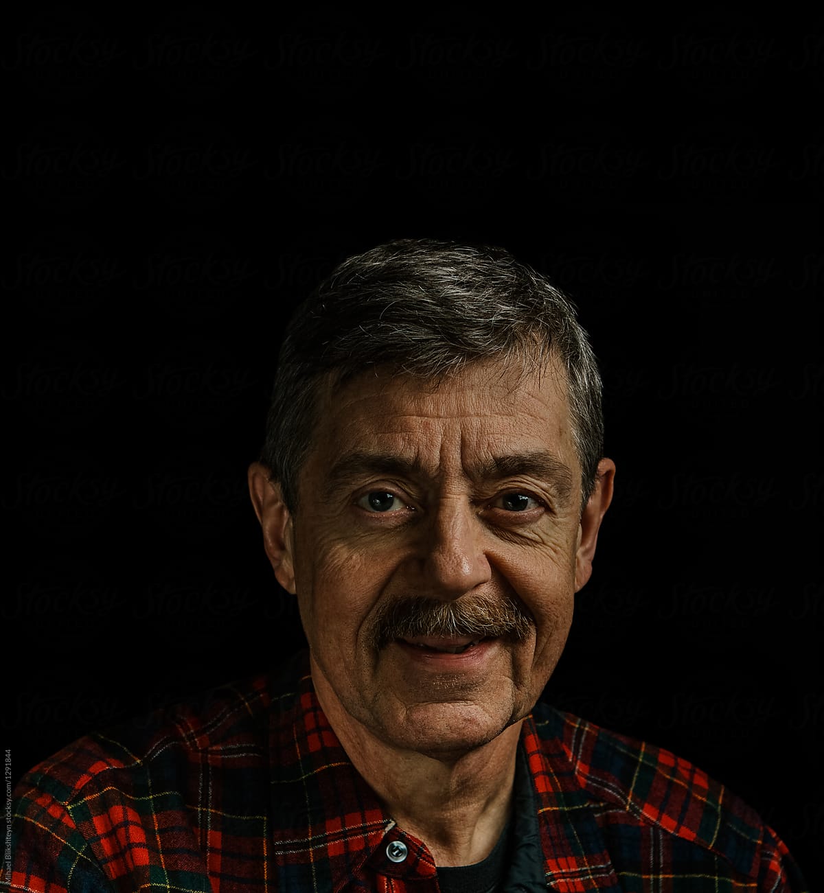 Portrait of a man in plaid button-up shirt isolated on a black background