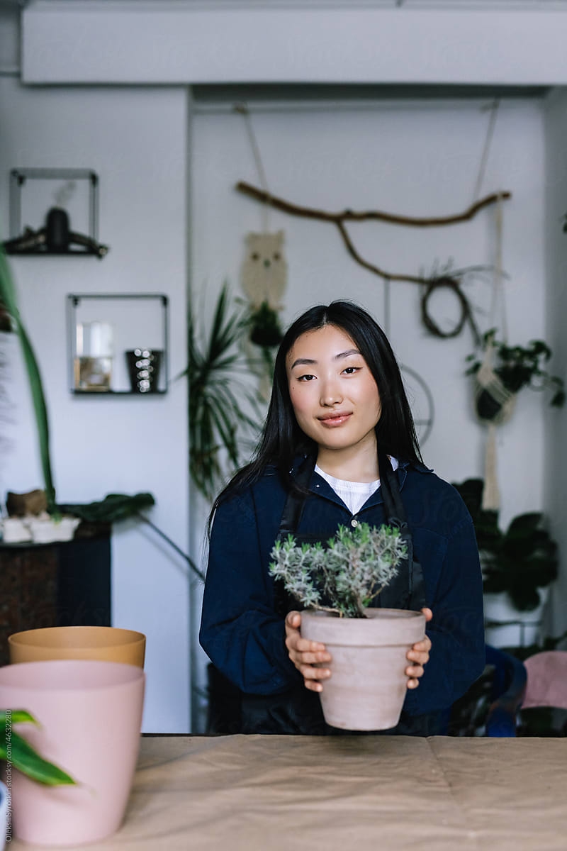 Asian seller with potted plant in contemporary floral shop
