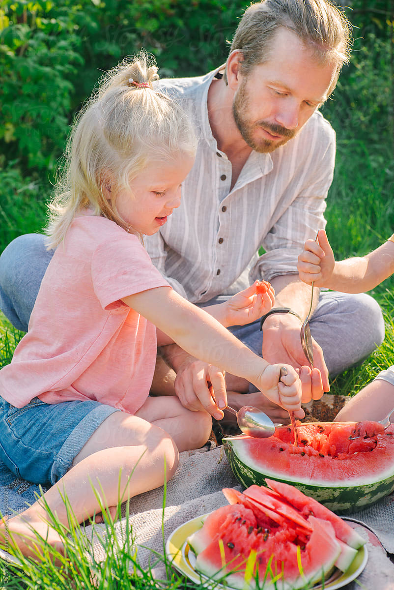 Daughter and father eat watermelon with a spoon
