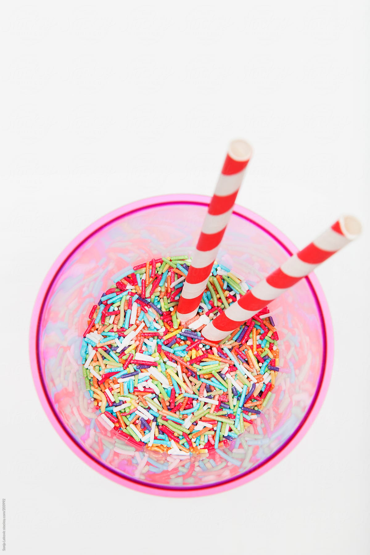 pink glass with sugar sprinkles and drinking straw