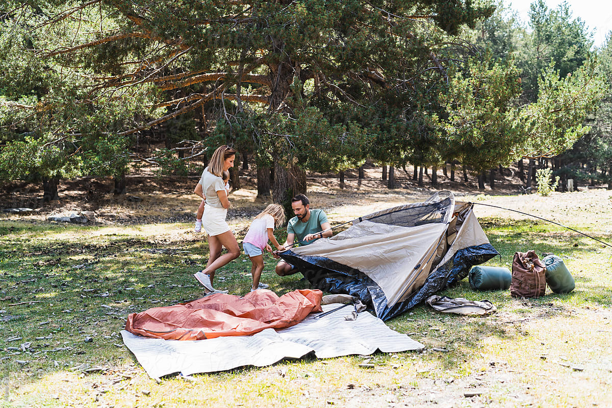 Family pitching tent near forest