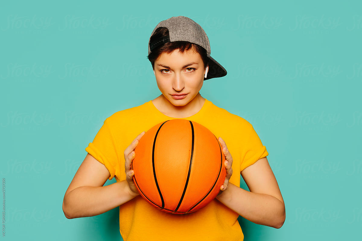 Girl in sporty outfit holding a basketball ball.