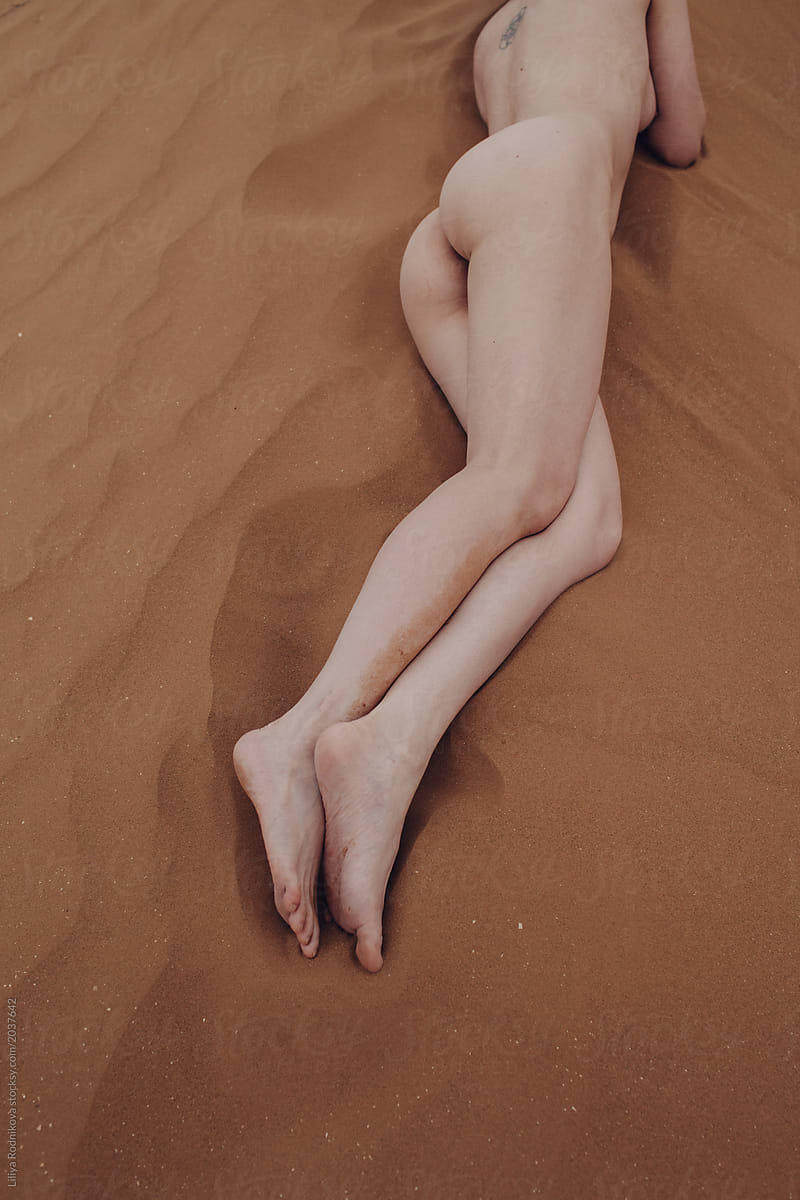 Crop female's beautiful legs by the desert sand