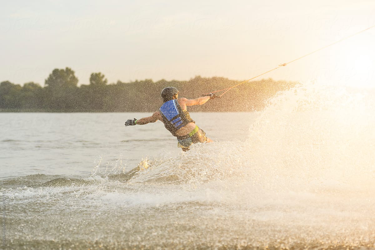 Male wakeboarder splashing the water while riding on the lake