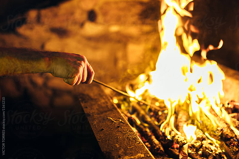 Closeup of a Mand Hand Preparing a BBQ at Night