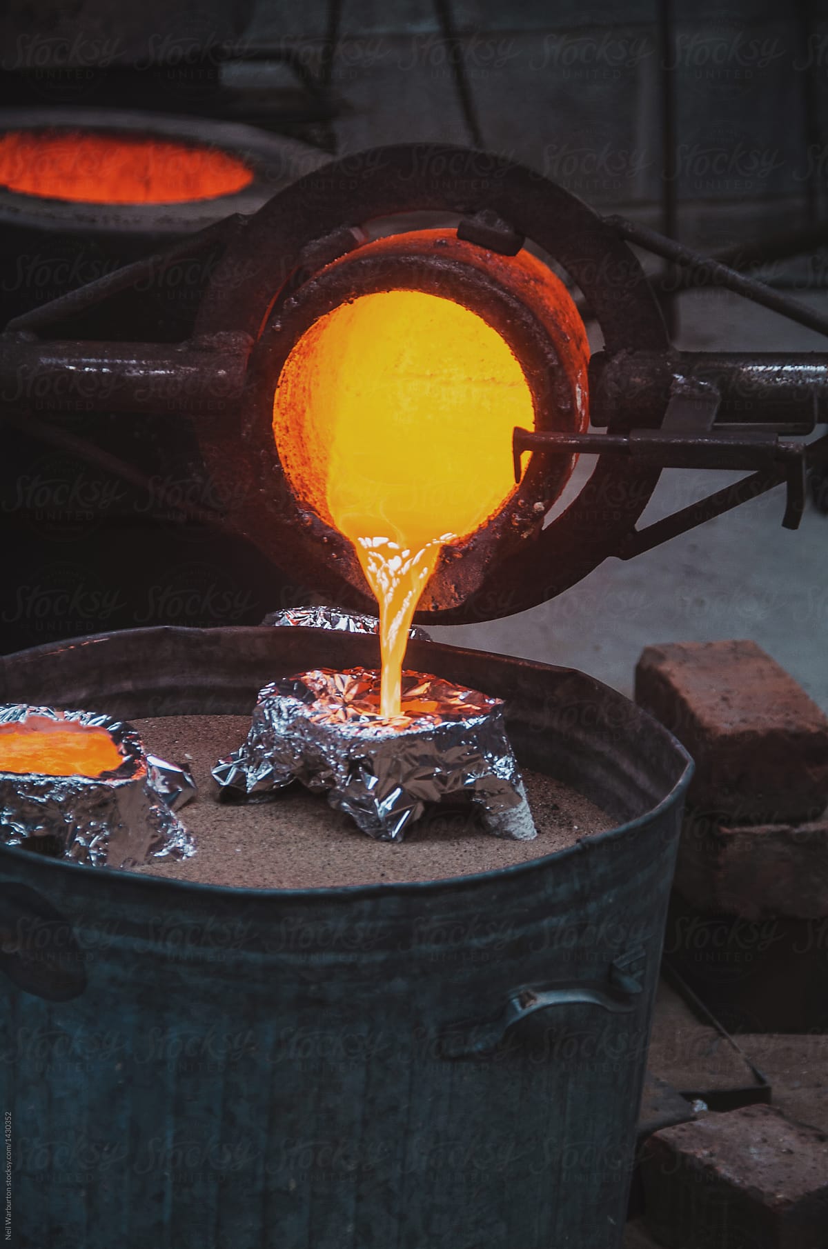 Pouring Molten Bronze Into Shell" by Stocksy Contributor "Neil Warburton" - Stocksy